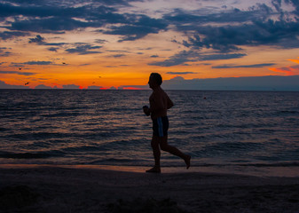 Fototapeta na wymiar Silhouette of running man against the colorful sky. Silhouette of running man on sunset fiery background