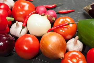 Vegetables. Peppers, tomatoes, garlic, eggplant, onions and radishes on a black background