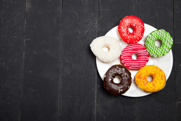 Colorful donuts on a black wooden background