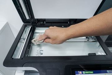 close up man clean glass plate of office printer with right hand