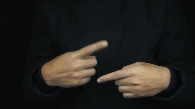 Caucasian male hands in long sleeve jacket twisting pointing fingers arounde on black background, close up isolated