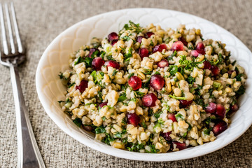 Wheat salad with pomegranate in white bowl.
