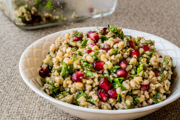 Wheat salad with pomegranate in white bowl.