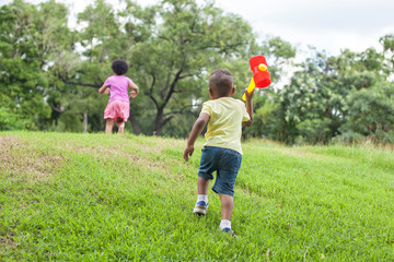 Fototapeta premium Kids running and chasing after each other in the green park in summer