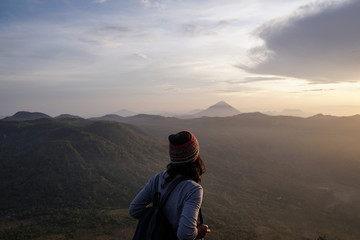 woman facing sunrise over mountain