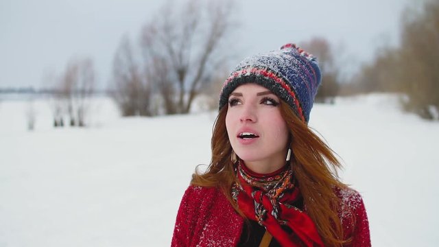 Portrait of young redhead woman inhaling cold air in snow field