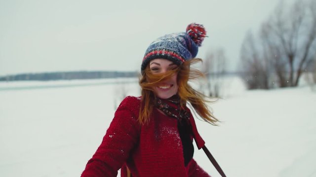 Young red hair woman enjoying snowfall outdoors, smiling and laugh looking at camera in slow motion 120fps