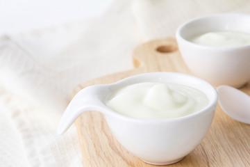 Close up natural creamy white yogurt in cup on wooden plate