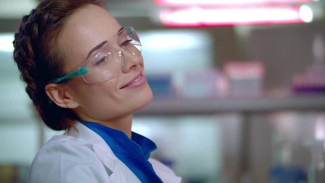 Chemist woman smiling. Close up of female chemist face in safety glasses. Smiling woman chemist in lab. Happy chemist scientist portrait. Smiling scientist in science lab