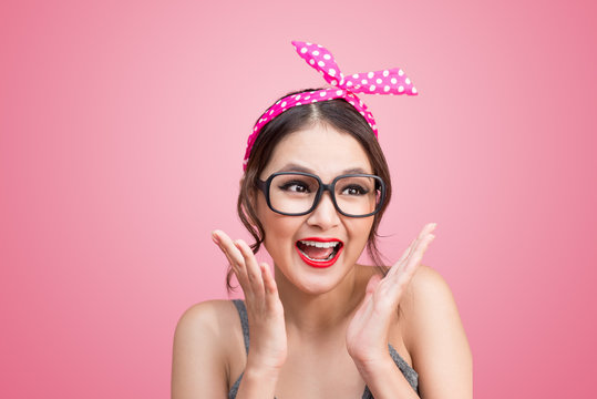 Fashion portrait of asian girl with sunglasses standing on pink background.