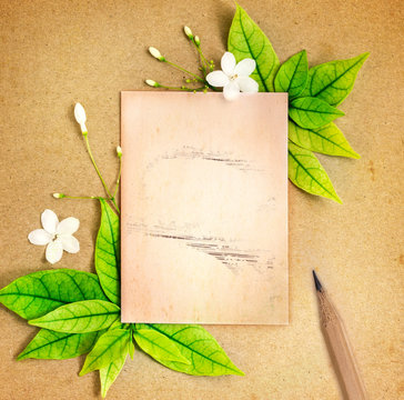 The old blank paper sheet with fresh spring  green leafs border frame on brown recycle paper background , eco natural banner concept