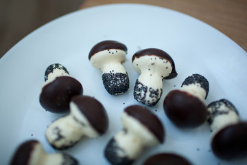 Cookies mushrooms glazed in white and brown chocolate on a white plate