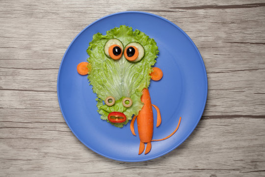 Vegetable monkey on blue plate and wooden table