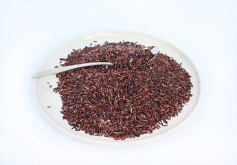 Jasmine red rice with spoon against white background.