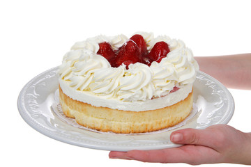 Female hands holding porcelain plate with large strawberry shortcake dessert isolated on white background