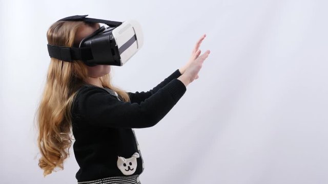Little blonde girl plays virtual reality game in studio. 