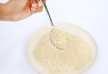 Hand holding Jasmine rice on spoon on white background.