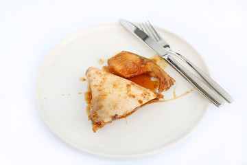 Hamachi cooked in Teriyaki sauce on ceramic plate against white background.
