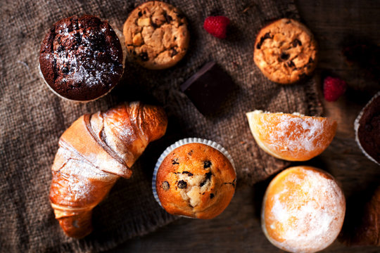 Delicious Chocolate muffins, croissants and dark chocolate pieces on wooden table  - Food background, bakery concept, close up image
