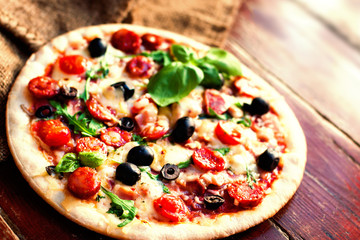 Delicious hot  pizza with salami, pepperoni and cheese on a dark background. Top view  Pizza circle  on  black table..
