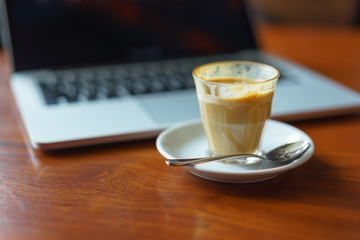 Breakfast with hot coffee latte and laptop in background on wooden table