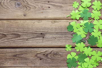 Paper clover leaves on the old wooden background. Space for text, top view.