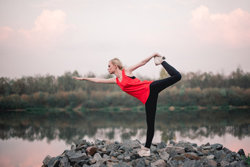 Young girl doing yoga fitness exercise outdoor near river landscape. Evening sunset, Namaste Lotus pose. Meditation and Relax