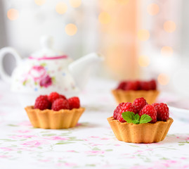 Three cupcakes with raspberries, mint on a table