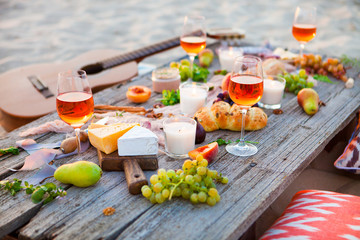 Picnic on the beach at sunset in boho style, food and drink concept