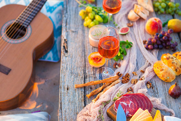 Picnic on the beach at sunset in boho style, food and drink concept