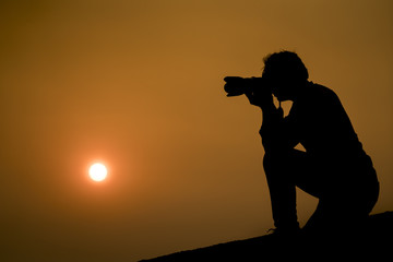 silhouette of photographer taking picture of landscape during sunset