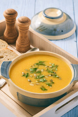 Yellow vegetable cream soup on wooden table.