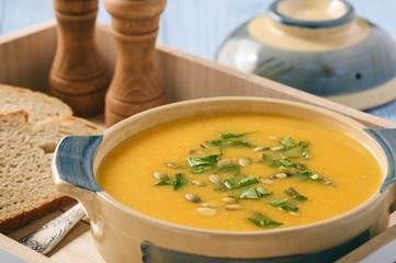 Yellow vegetable cream soup on wooden table.