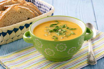 Yellow vegetable cream soup on wooden table.