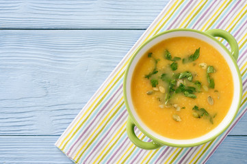 Yellow vegetable cream soup on wooden table.