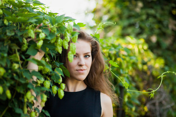 Attractive young woman in a green fence of fresh hop