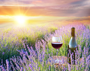 Bottle of wine against lavender landscape with romantic sunset.