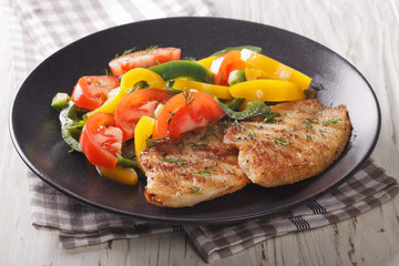 Fried tilapia fillet, fresh salad with pepper and tomato close-up. horizontal
