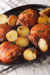 Roast chicken thighs and baby potatoes with maple syrup closeup. vertical