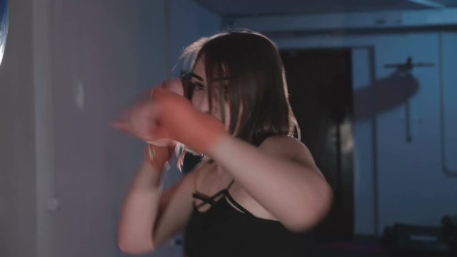 Pretty kickboxing woman training punching bag in sport studio in 4K