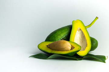 Whole avocado with leaves and cut half seed isolated on white background as package design element