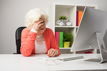 Older woman at the office don't know how to use computer - obrazy, fototapety, plakaty