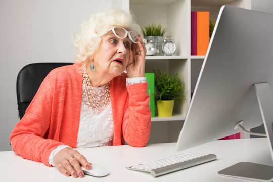 Grandma working at the office and looking at the computer in disbelief