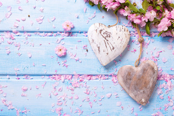 Two vintage decorative hearts and pink sakura  flowers on blue wooden planks