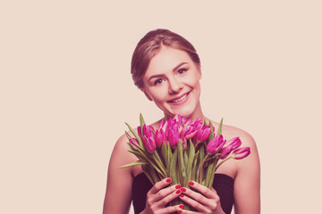 Portrait of beautiful young woman with long hair and glamour makeup. Girl holding tulips. Studio shot.