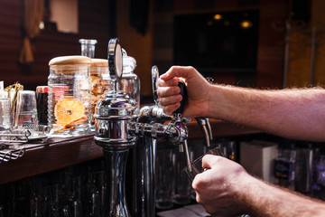 Close-up of bartenders hands pouring beer