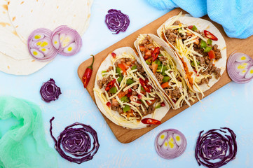 Spicy Mexican tacos with minced meat, mashed beans, vegetables, grated cheese. The top view