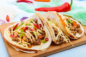 Spicy Mexican tacos with minced meat, mashed beans, vegetables, grated cheese.