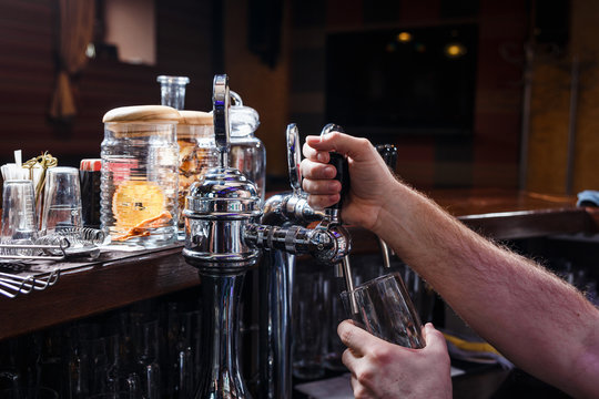 Close-up of bartenders hands pouring beer