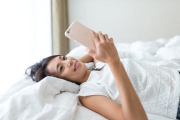 Woman using cellphone and lay down on bed